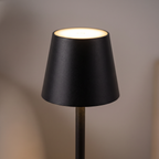 Detalle de la pantalla de aluminio mate negro de la lámpara Nomad y su difusor encendido