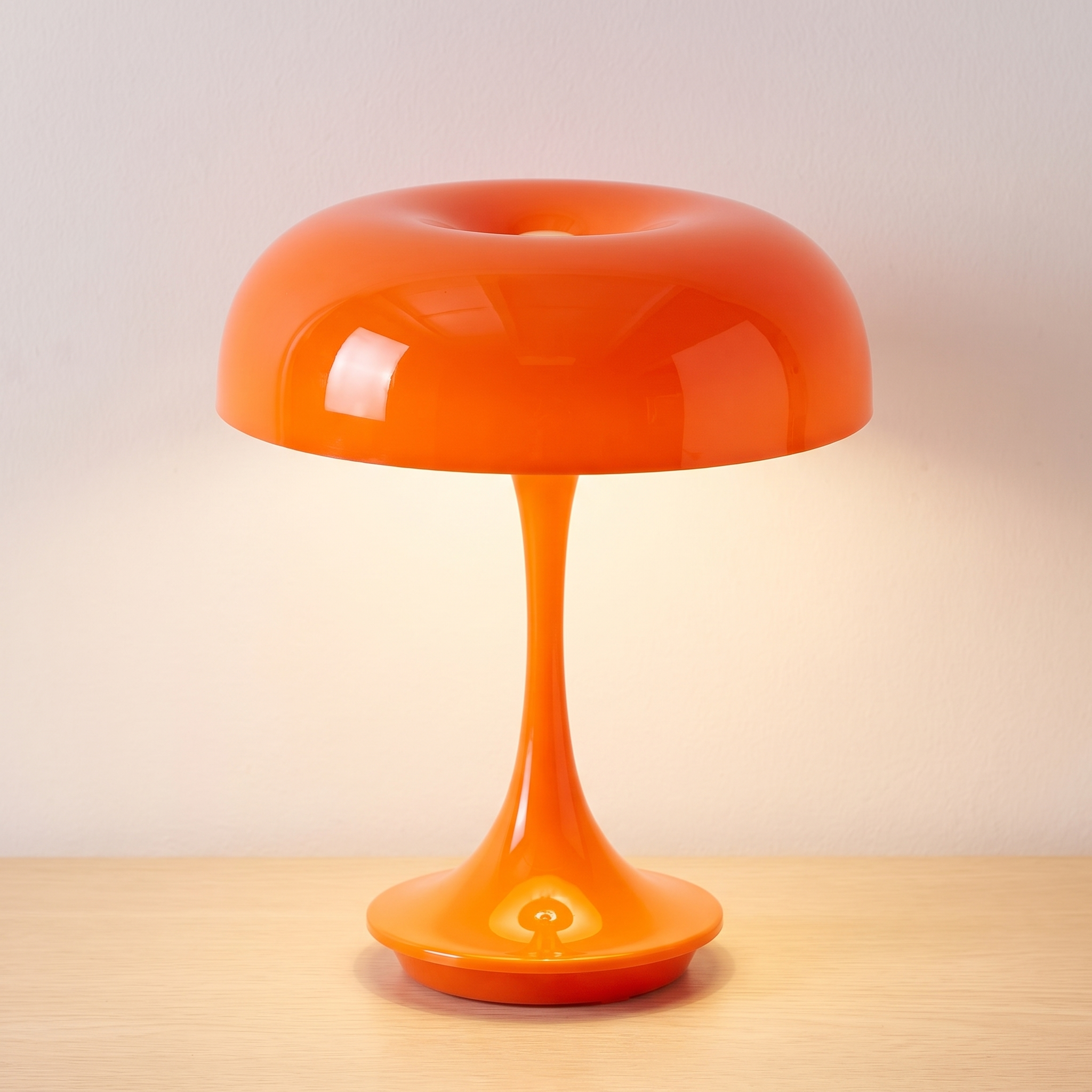 Lámpara de mesa seta Mila en naranja brillante, encendida sobre una superficie de roble