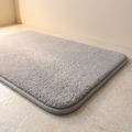 Alfombra de baño gris claro 50x80 de pelo largo en suelo de piedra