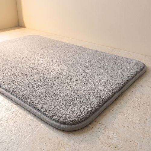 Alfombra de baño gris claro 50x80 de pelo largo en suelo de piedra