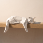 Figura decorativa de gato geométrico blanco en el borde de una balda