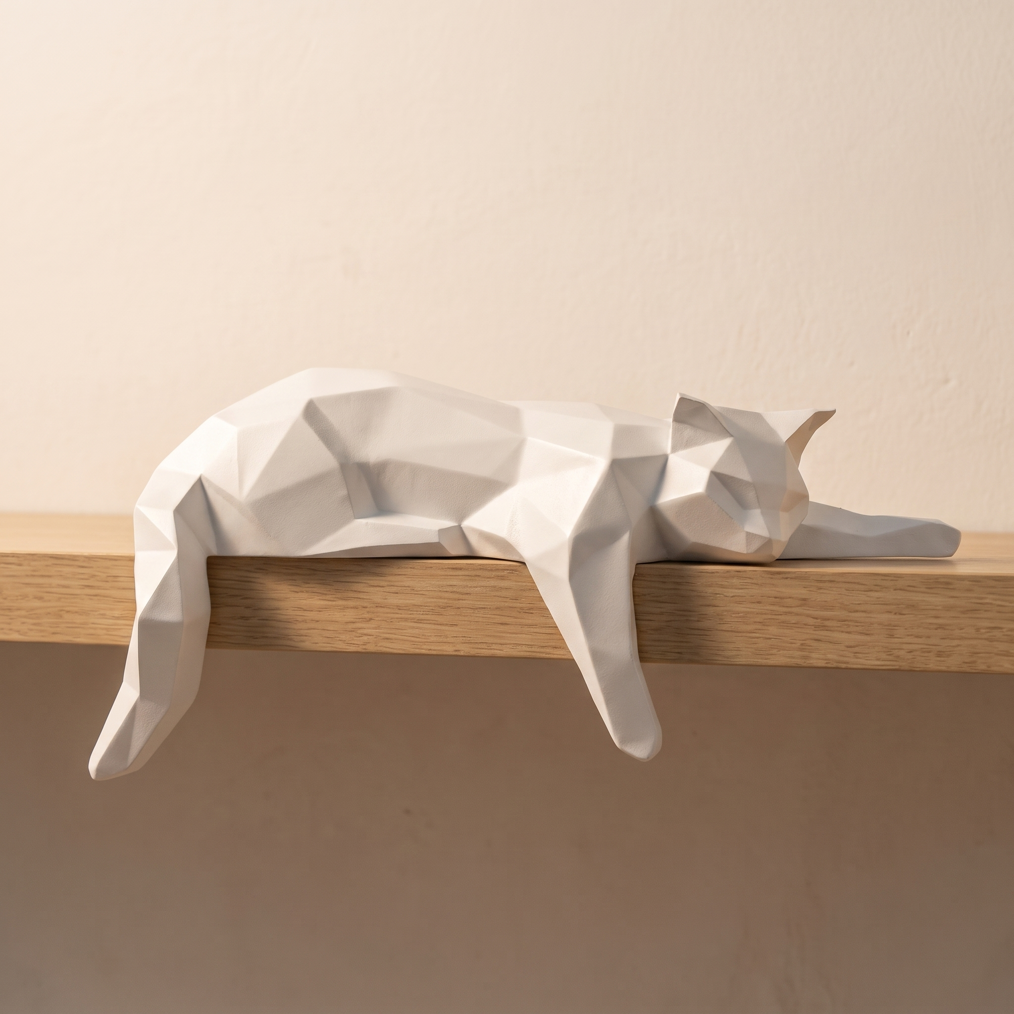 Figura decorativa de gato geométrico blanco en el borde de una balda