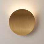 Aplique de pared LED redondo dorado encendido sobre pared clara
