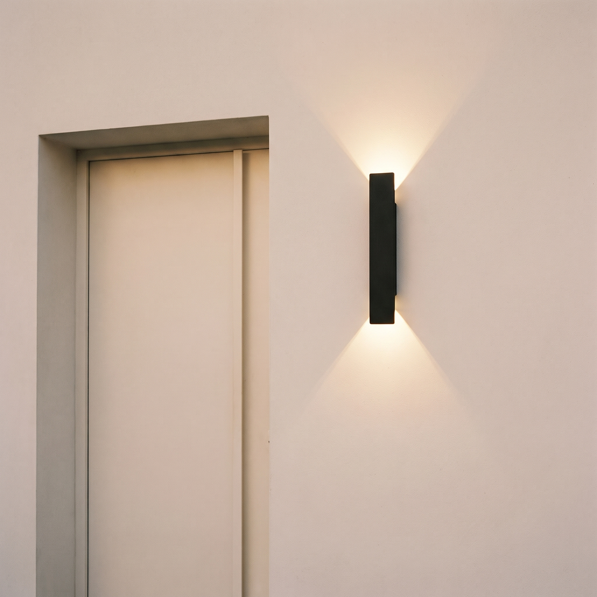 Aplique vertical negro junto a la puerta de entrada al anochecer